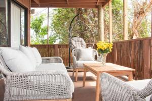 porche con sillas de mimbre, mesa y columpio en Sea View & Sunset Haven, en Enighed