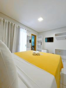 Un dormitorio con una cama amarilla con dos anillos. en Pousada Unaí, en Porto de Galinhas
