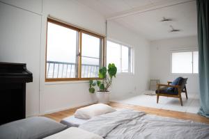 a bedroom with a bed and a chair and windows at 【湯布院の山小屋】サンクラウド・ヒュッテ in Yufuin