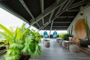 eine Veranda mit Stühlen, Tischen und Pflanzen in der Unterkunft ARTOTEL Sanur Bali in Sanur