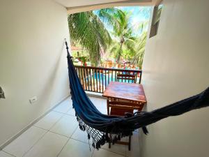 a hammock in a room with a table and palm trees at Pousada Unaí in Porto De Galinhas