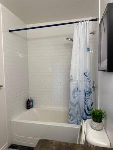 Baño blanco con bañera y cortina de ducha en Luxury Spacious 5-Bedroom Home en Londres