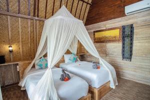 - 2 lits dans une chambre dotée de rideaux blancs dans l'établissement Desa Sweet Cottages, à Nusa Lembongan