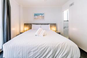 Un dormitorio con una cama blanca con dos toallas encima. en Olympus Beachfront Apartments, en Gold Coast