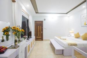 Habitación blanca con cama y mesa con flores en Lis Hotel en Da Nang