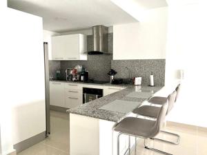 a kitchen with white cabinets and a counter with stools at Villa parmera in Los Corrales