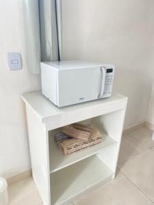 un microondas en la parte superior de un estante blanco en Suite Brava, en Búzios 8 fotos más