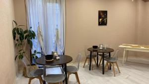 duas mesas e cadeiras numa sala com uma planta em Astoria Hotel em Zugdidi