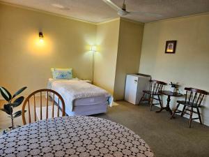 a bedroom with a bed and a table and a refrigerator at Park Lodge Motel in Te Awamutu