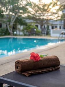 a towel with a flower sitting on a table next to a pool at Isara Nai Yang resort in Nai Yang Beach