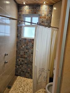 a bathroom with a shower with a toilet and a window at Cabañas Gardenias 2 in Zacatlán