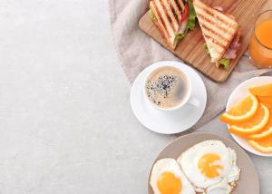 a plate of food with a sandwich and a cup of coffee at Frankstay By Hotel Mayfair Residency in New Delhi