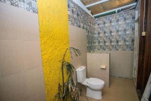 a bathroom with a toilet and a yellow wall at Desa Sweet Cottages in Nusa Lembongan