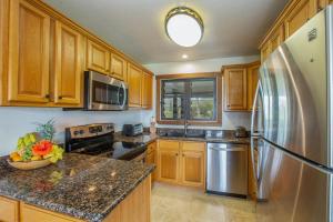 a kitchen with wooden cabinets and a stainless steel refrigerator at Kaha Lani 304 in Lihue +18 photos