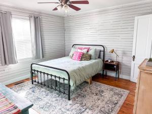 a bedroom with a bed with pink pillows and a ceiling fan at The Grate House - Fire Table - Grill - Fenced Yard in Searcy