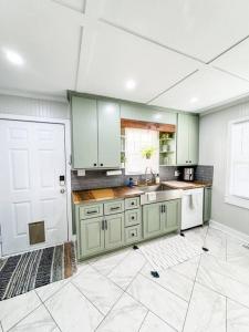 a kitchen with green cabinets and a white door at The Grate House - Fire Table - Grill - Fenced Yard in Searcy
