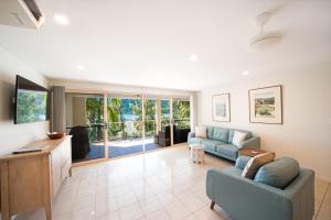 a living room with a couch and a tv at Le Jarden Vu Du Port in Airlie Beach