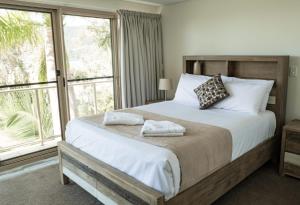 a bedroom with a large bed and a large window at Le Jarden Vu Du Port in Airlie Beach