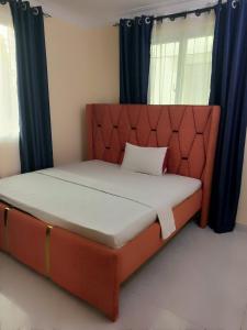 een bed in een kamer met blauwe gordijnen bij Lizzy B Classic Apartments Mtwapa in Mombasa