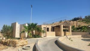 a house with a road in front of a mountain at Comfy Stays Sea View Apartments at DeadSea Samarah Resort in Sowayma