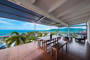 a house with a deck with a table and chairs at Nautilus On The Hill - Airlie Beach in Airlie Beach