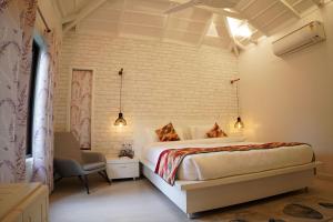 a bedroom with a bed and a chair in a room at amã Stays & Trails Whispering Pines, Bhimtal in Bhīm Tāl