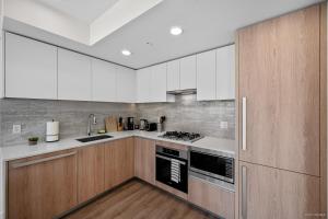 a kitchen with white cabinets and a stove top oven at Richmond City Center Brand New 1 Bedroom 4 Guests Apartment in Richmond