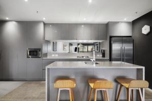a kitchen with a counter with three stools at Sky High Views in the Heart of Canberra in Canberra