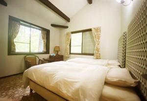 Un dormitorio con una gran cama blanca y una ventana en 绿之村豪華な天然温泉リゾートマンション 和モダンと和の融合 bbq を満喫 山林の湯の風雅, en Hakone