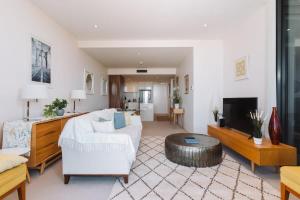 a living room with a white couch and a table at 1-Bed with Amazing Views, Pool, Gym, BBQ & Parking in Canberra
