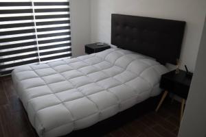 a large white bed in a bedroom with a window at Departamento en Guadalupe in Monterrey