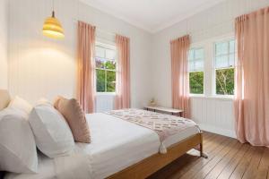 a bedroom with a large white bed with pink curtains at Daisy's Beach House - 16 Burns St Byron Bay in Byron Bay