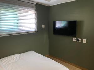 hola! Hostel في جيجو: غرفة نوم بسرير وتلفزيون بشاشة مسطحة