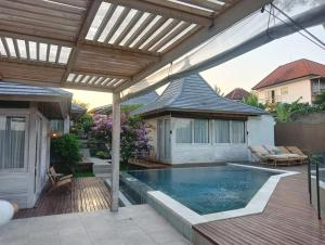 un patio con piscina y pérgola en Stay at My Place Bali en Canggu