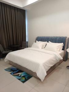 una camera da letto con un grande letto con lenzuola e cuscini bianchi di RJ Studio Apartment 1 - Hotel Mutiara a Gua Musang