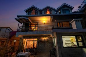 a large house with a person sitting on the balcony at Alaya Stays Meridian Oak, Shimla in Shimla