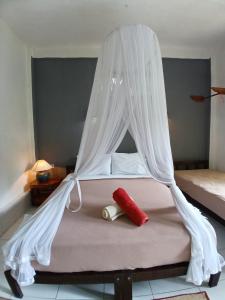 ein Bett mit weißen Moskitonetzen darüber in der Unterkunft JOSEPH GUEST HOUSE in Kelimutu