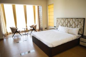 a bedroom with a large bed in a room with windows at Falak Farms- Villa with Pool,Jacuzzi in Chandigarh in Khizrābād