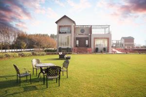 a house with chairs and a table in a field at Falak Farms- Villa with Pool,Jacuzzi in Chandigarh in Khizrābād