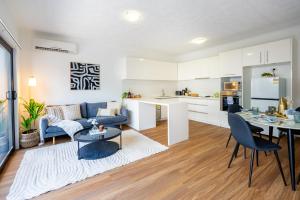 cocina y sala de estar con sofá azul y mesa en Balmoral Apartment - Airy & Light-filled City Edge Comfort Stay en Brisbane