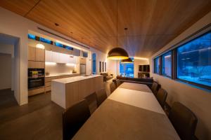 a kitchen and living room with a long table and chairs at Eminence by The Hakuba Collection in Hakuba