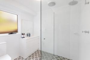 uma casa de banho branca com um lavatório e um chuveiro em Barnhill Beach House - Amazing Views em Terrigal