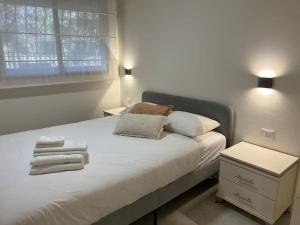 a bedroom with a white bed with towels on it at Garden House By IsrApart in Ra‘ananna