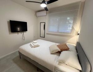 a bedroom with a bed with a flat screen tv at Garden House By IsrApart in Ra‘ananna