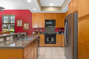 cocina con paredes rojas y nevera de acero inoxidable en Big Island Waikoloa Colony Villas 801 condo, en Waikoloa