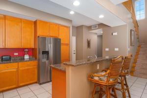 a kitchen with wooden cabinets and a stainless steel refrigerator at Big Island Waikoloa Colony Villas 801 condo in Waikoloa