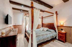 um quarto com uma cama de dossel e uma televisão em G&S Rustic House em San Pancrazio Salentino