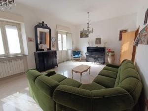 een woonkamer met een groene bank en een piano bij Casa Etna in Solicchiata