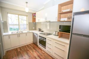a large kitchen with white cabinets and a window at Silver Birches Holiday Village - Unit 6 in Bright