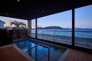 een zwembad met uitzicht op het water bij Villa JacoO-ヴィラじゃこまる- in Sanuki